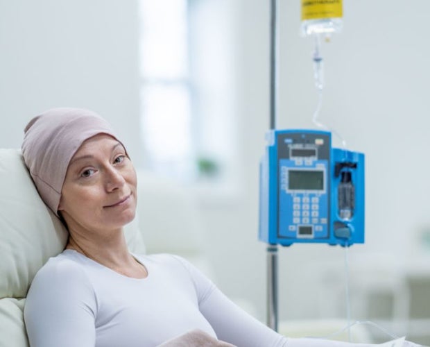 Middle-aged woman in a hospital bed. She is going through chemotherapy and has a cap on.